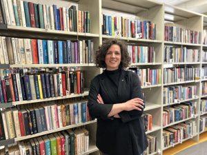 Baiba Īvāne bibliotēkā pie grāmatu plauktiem