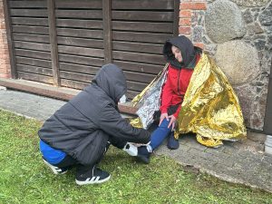 Cilvēks sniedz palīdzību sievietei ar savainotu kāju pirmās palīdzības apmācībās