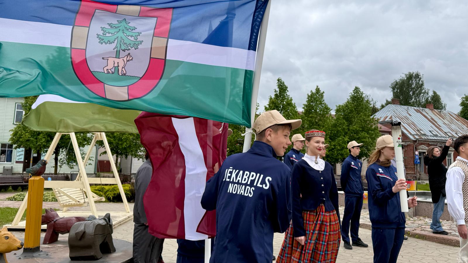 Jēkabpilī jaunie sportisti un pasākuma dalībnieki sagaida Latvijas Jaunatnes X olimpiādes lāpu.
