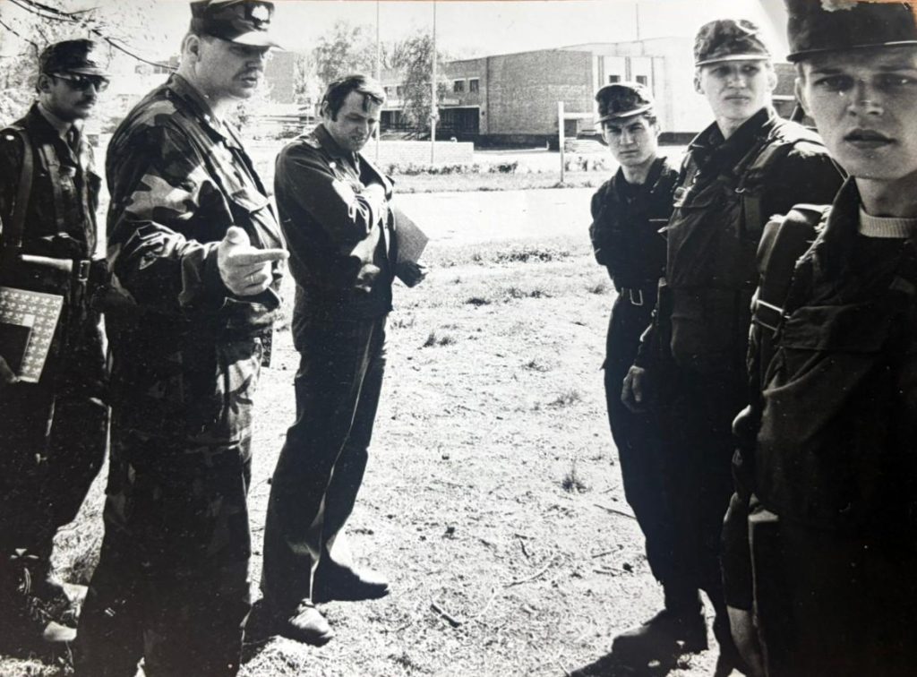 Vīrieši militārā apģērbā saņem norādījumus brīvā dabā