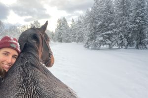 Sieviete ar zirgu ziemas ainavā sniegotā mežā