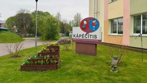 Bērnudārza “Kāpēcītis” teritorija ar iestādes nosaukuma stendu