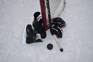 Hokeja slidas, nūja, ripa un cimdi pie vārtiem uz ledus laukuma