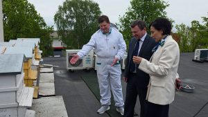 Cilvēki apskata urbānās bišu saimes uz ēkas jumta Jelgavā