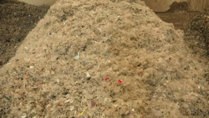 Sasmalcinātu plastmasas un iepakojuma atkritumu kaudze pārstrādes uzņēmumā.