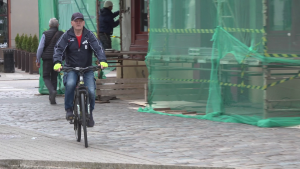 Vīrietis brauc ar velosipēdu pa pilsētas ielu