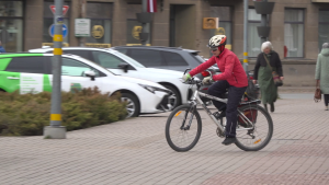 Sieviete ar velosipēdu pārvietojas pa pilsētas centru