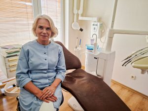 Zobārste Ilze Kantāne zobārstniecības kabinetā pie pacienta krēsla