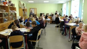 Skolēni klasē piedalās radošā nodarbībā, strādājot grupās pie zīmēšanas un citiem uzdevumiem pedagogu vadībā.