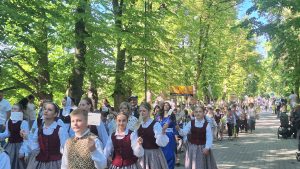 Bērni un jaunieši tautastērpos dodas svētku gājienā pa koku ieskautu parka aleju kultūras pasākuma laikā.