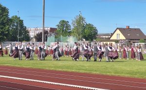 Tautas deju kolektīvu dalībnieki tautastērpos uzstājas stadionā brīvdabas pasākuma laikā.