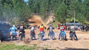 Motokrosa braucēji startē sacensībās uz smilšu trases.
