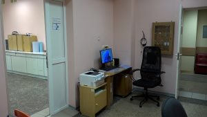 Darba vieta Steidzamās medicīniskās palīdzības punktā ar datoru un piekļuvi pacientu apskates telpai.
