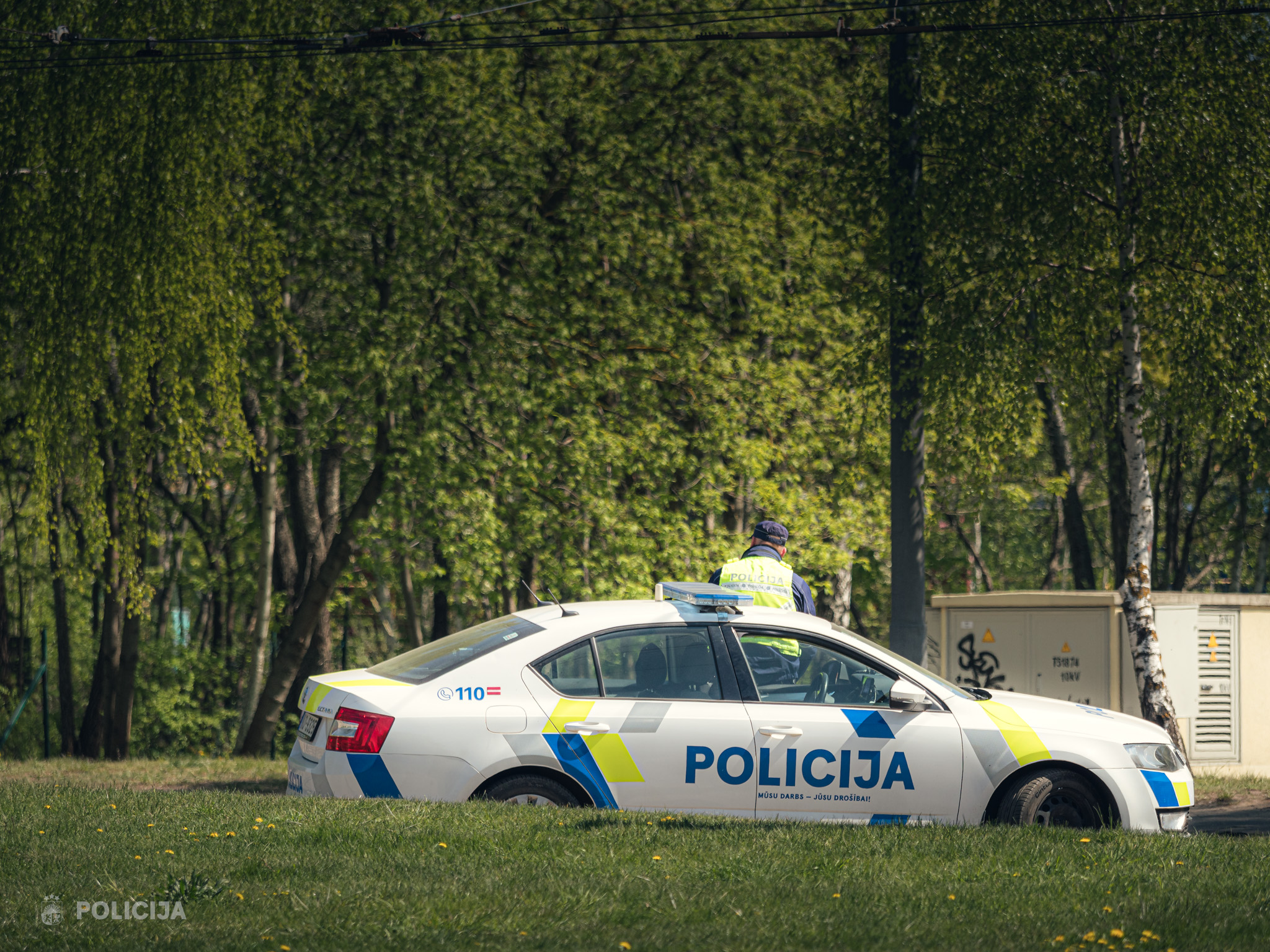 Valsts policijas automašīna un policists dienesta pienākumu izpildes laikā.