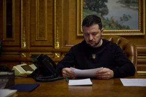 Ukrainas prezidents sēž pie rakstāmgalda un lasa dokumentu savā darba kabinetā.