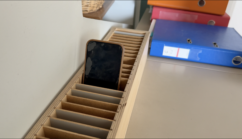 Mobilais telefons ievietots īpašā koka uzglabāšanas kastē.