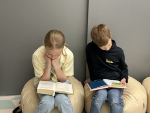 Divi bērni bibliotēkā lasa grāmatas vasaras lasīšanas iniciatīvas laikā.