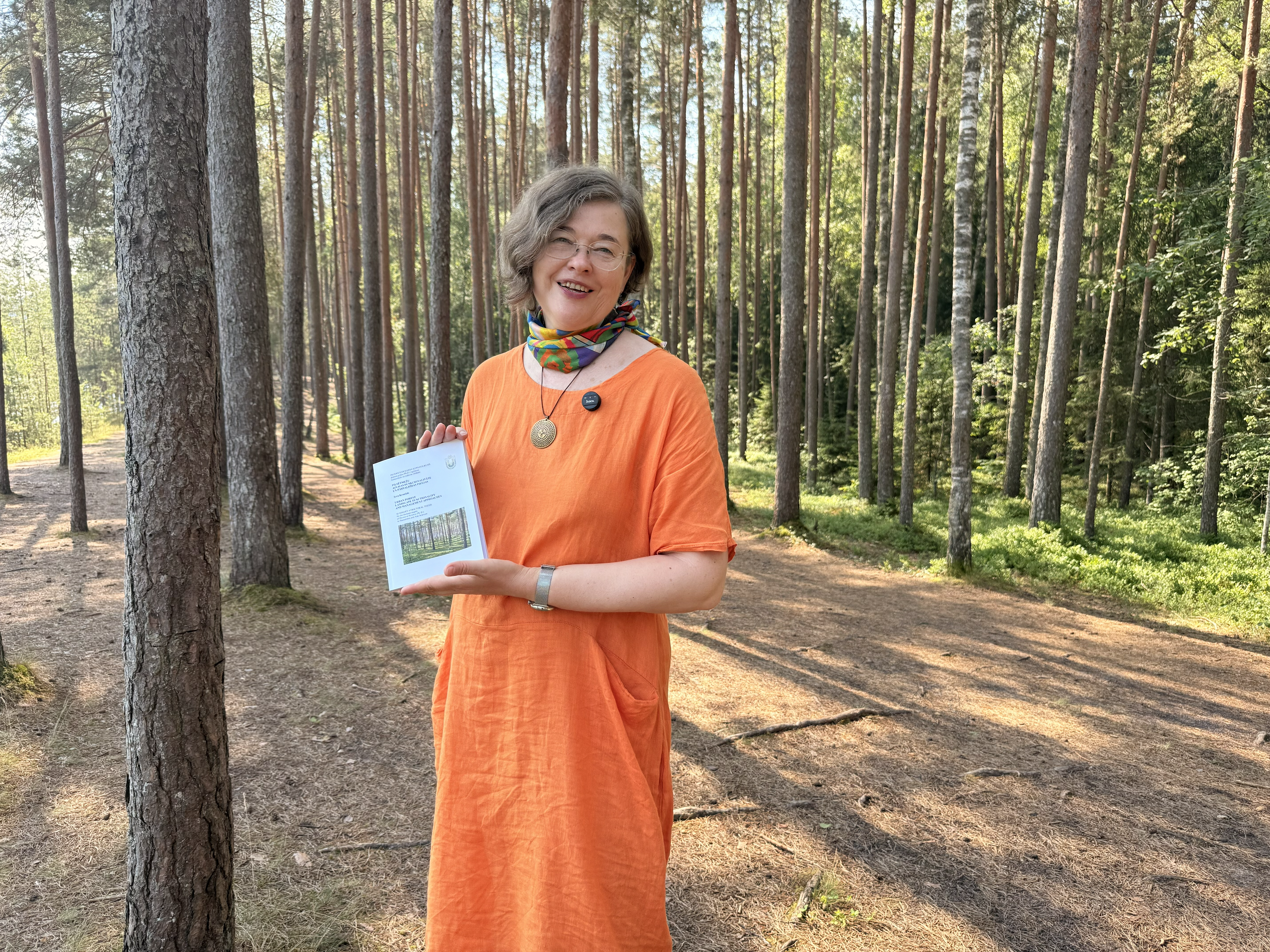 Zinātniece Ieva Kraukle pilsētmežā prezentē savu promocijas darbu par pilsētmežu nozīmi Latvijā.