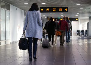 Cilvēki ar bagāžu dodas pa lidostas termināli ārvalstu ceļojuma laikā.