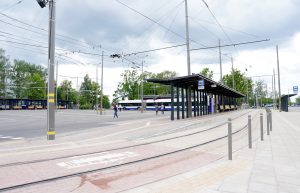 Sabiedriskā transporta pieturvieta ar tramvaja sliedēm un autobusiem pilsētvidē.