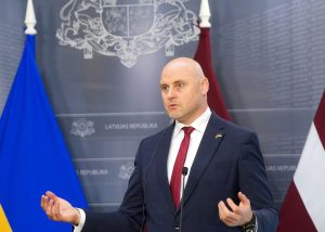 Ministru prezidents Andris Kulbergs uzstājas preses konferencē pie runas pults, fonā redzami Latvijas un Ukrainas karogi.