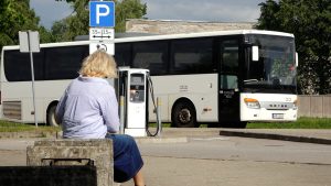 Autobuss pieturvietā pie pasažieres reģionālā sabiedriskā transporta maršrutā.