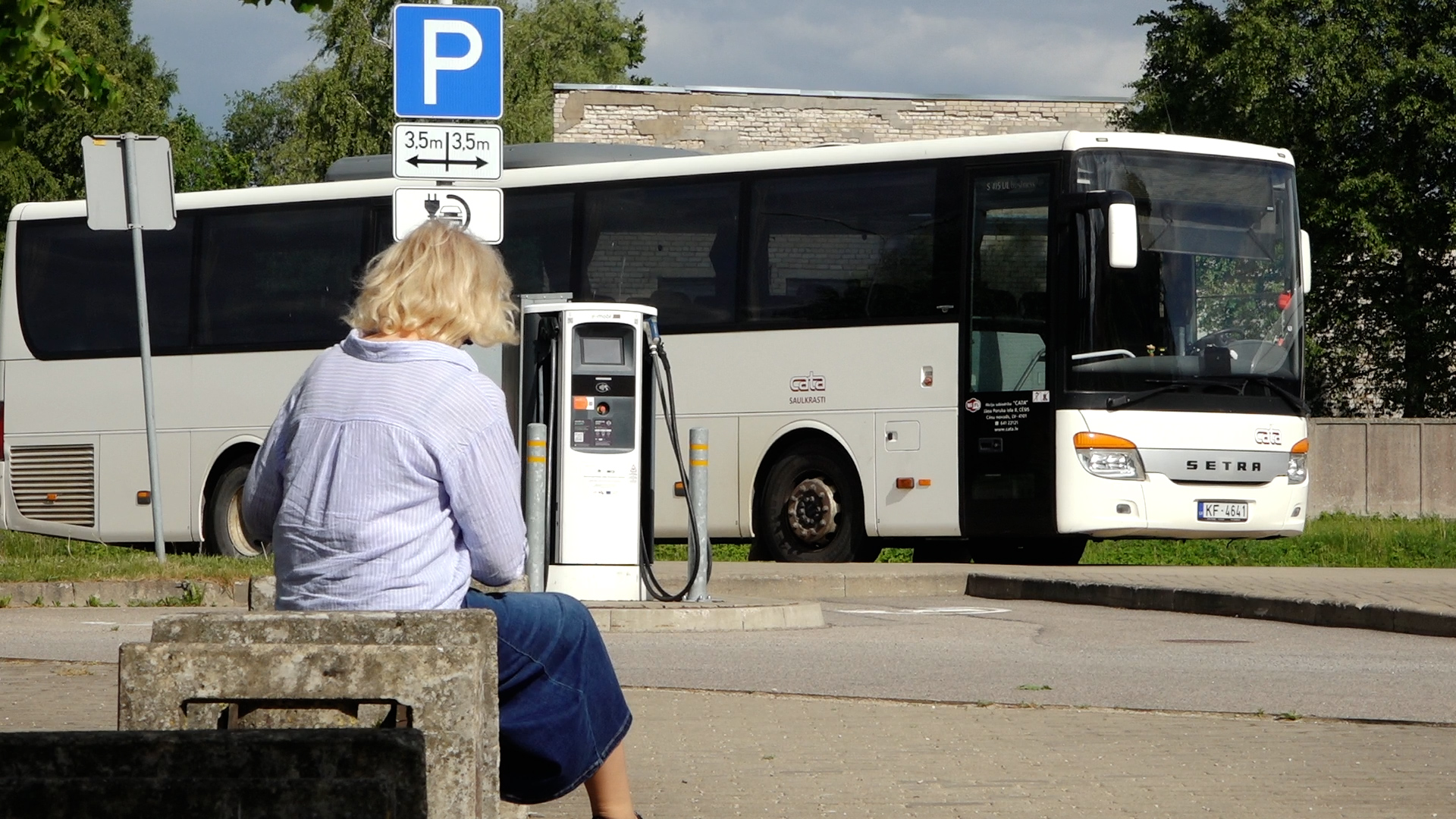 Autobuss pieturvietā pie pasažieres reģionālā sabiedriskā transporta maršrutā.