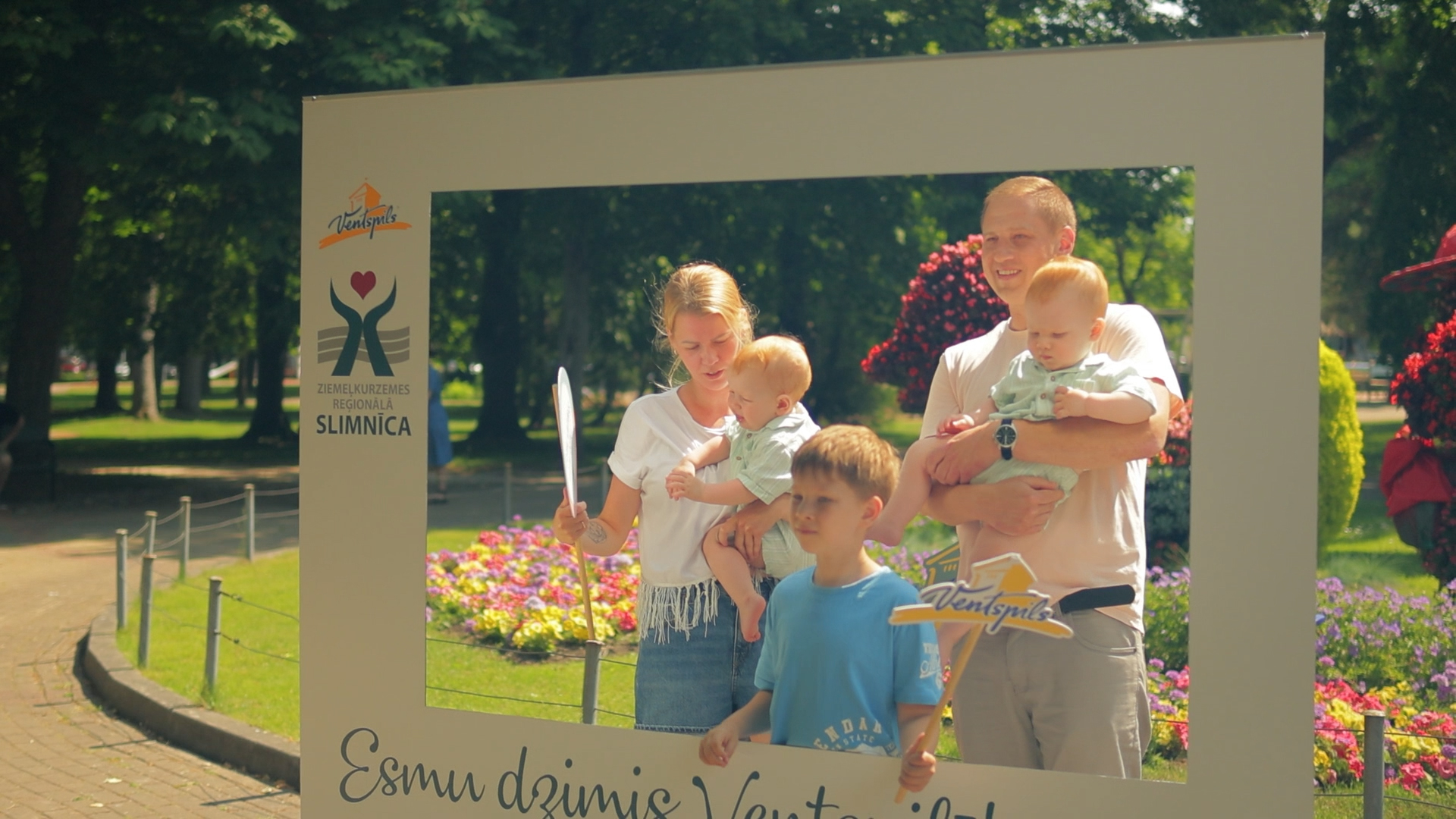 Ģimene ar trim bērniem fotografējas pasākumā 