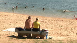 Cilvēki atpūšas un peldas pludmalē karstā vasaras dienā.