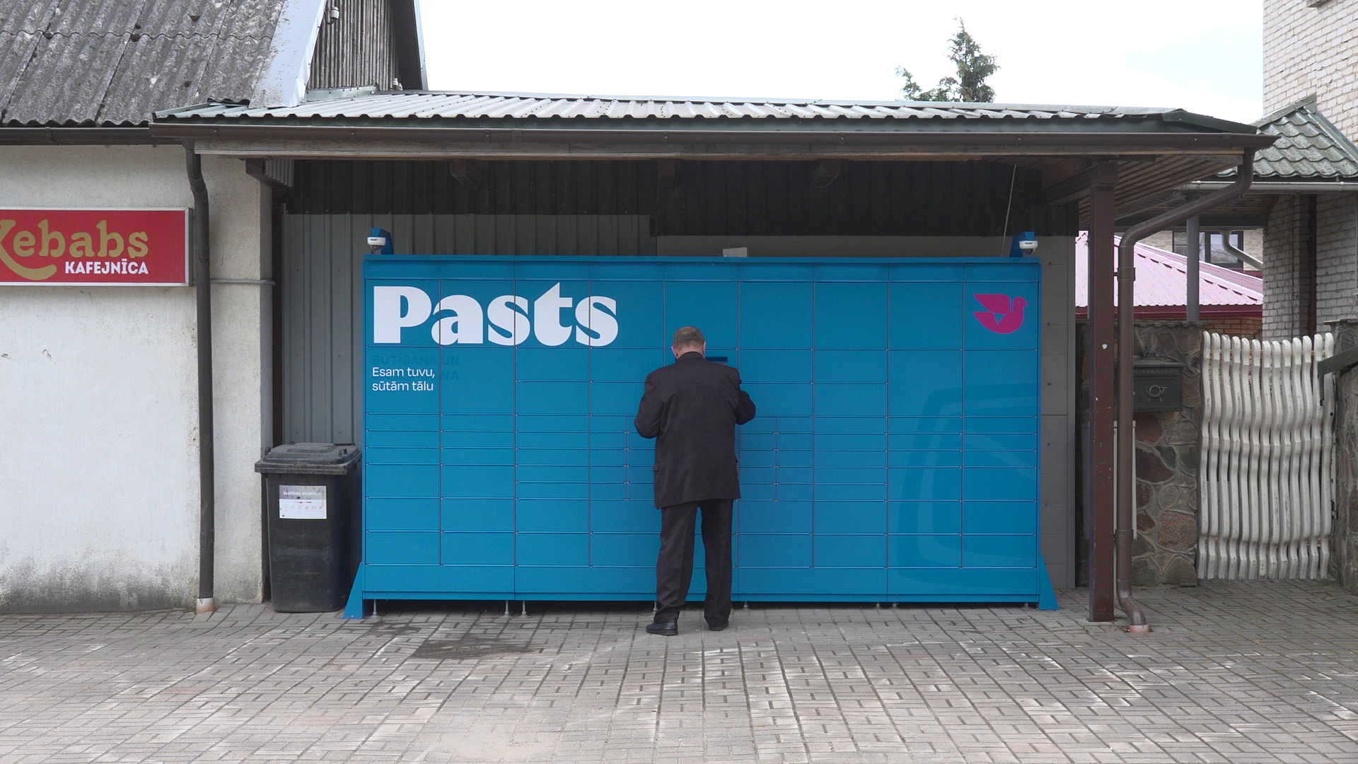 Cilvēks saņem sūtījumu no Latvijas Pasta pakomāta.