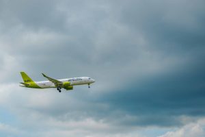 airBaltic pasažieru lidmašīna lido mākoņainās debesīs pirms nosēšanās.