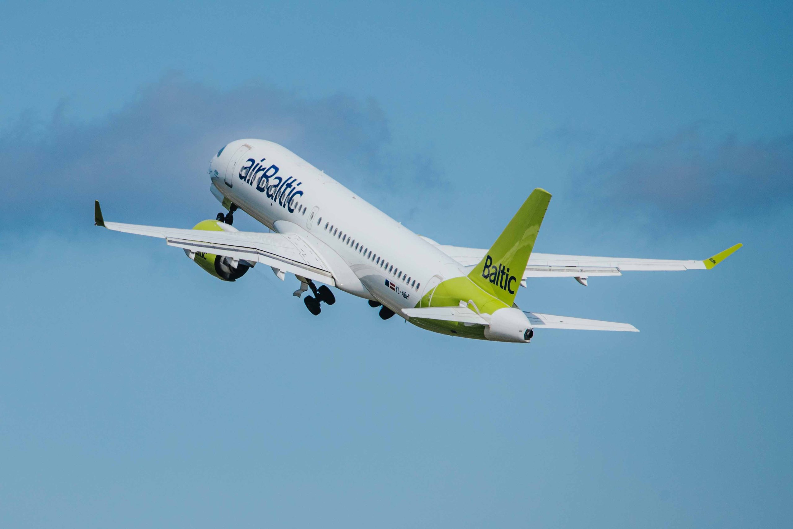 airBaltic pasažieru lidmašīna paceļas lidojumā zilās debesīs.