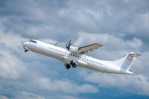 Turbopropelleru pasažieru lidmašīna paceļas lidojumā mākoņainās debesīs.