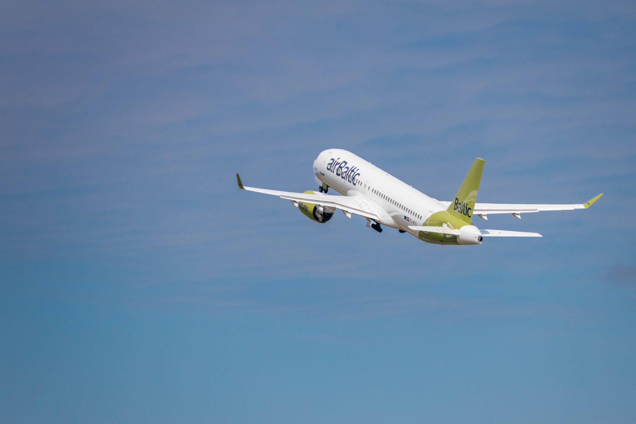airBaltic pasažieru lidmašīna paceļas debesīs pēc izlidošanas no lidostas.