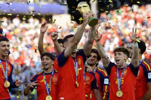 Spānijas futbola izlases spēlētāji svin uzvaru Pasaules kausā, paceļot čempionu trofeju.