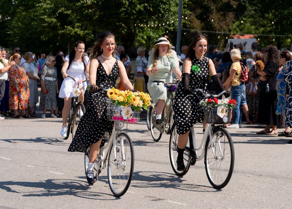 Dalībnieces retro tērpos ar izrotātiem velosipēdiem piedalās Ērenpreisa svētku velobraucienā Mazsalacā.