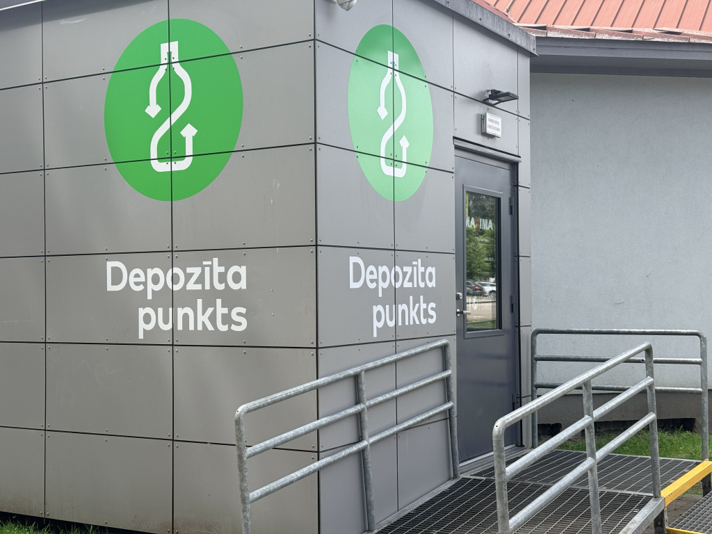 Depozīta punkta ēka ar ieeju un depozīta sistēmas simboliem.