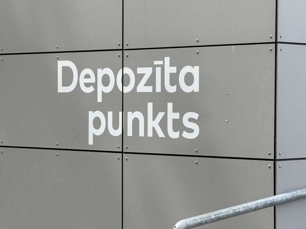 Uz ēkas sienas redzams uzraksts "Depozīta punkts".
