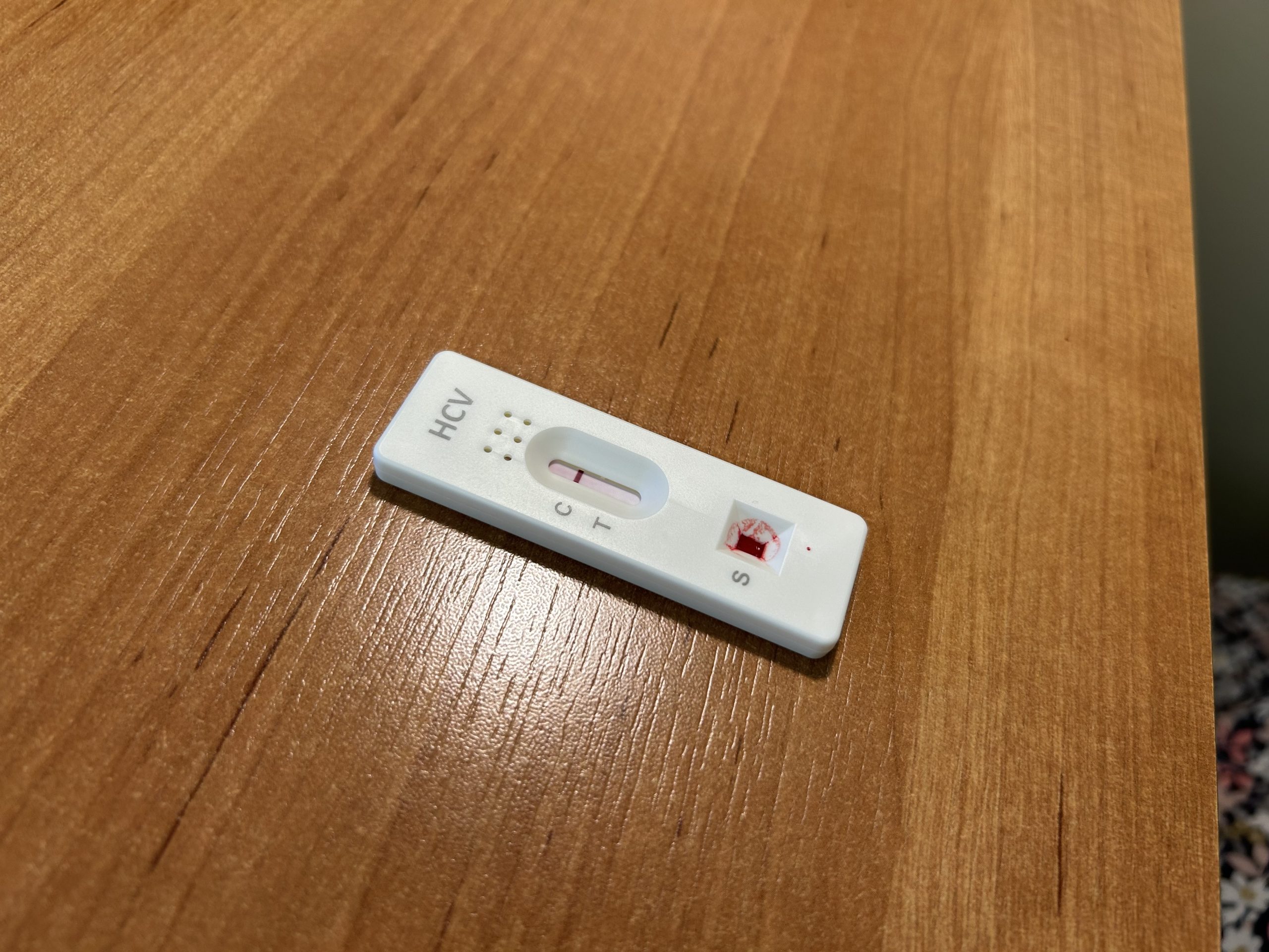 Ātrais C hepatīta tests ar asins paraugu uz galda.