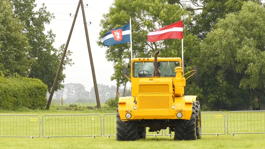 Dzeltenais traktors ar karogiem tradicionālajā traktordienā Tērvetē.