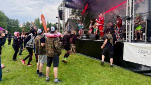 Festivāla "Munky Pride" apmeklētāji dejo un klausās koncertu pie skatuves.