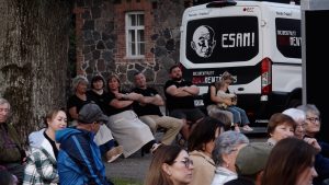 Skatītāji brīvdabas kino seansā pie dokumentālā kino autobusa "ESAM!".