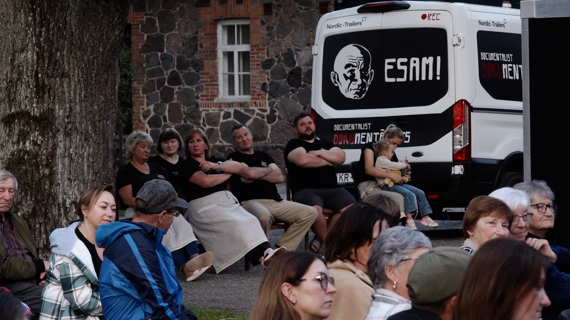 Skatītāji brīvdabas kino seansā pie dokumentālā kino autobusa 