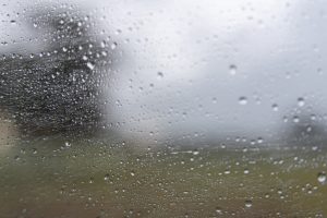 Lietus lāses uz loga stikla lietainā un apmākušā dienā.