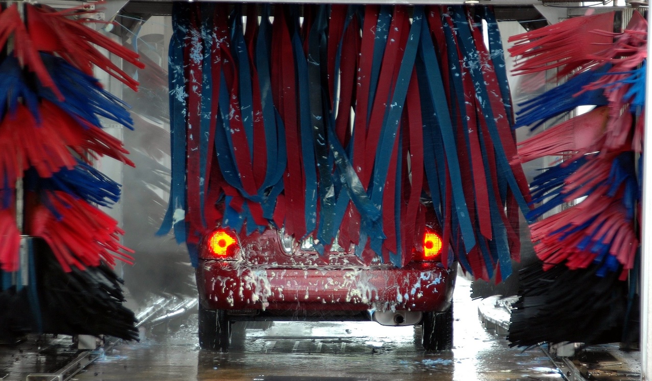 Automašīna automātiskajā auto mazgātavā, kur virsbūvi tīra rotējošas birstes.