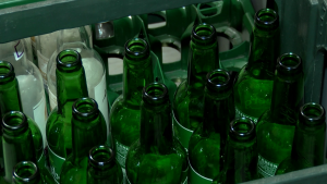 Tukšas stikla pudeles plastmasas kastē, kas sagatavotas atkārtotai izmantošanai vai pārstrādei.