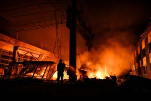 Glābējs dzēš ugunsgrēku degošā tirdzniecības kompleksā Zaporižjā pēc Krievijas dronu uzbrukuma.