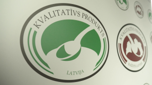 Marķējuma "Kvalitatīvs produkts Latvija" logotips uz informatīva stenda.
