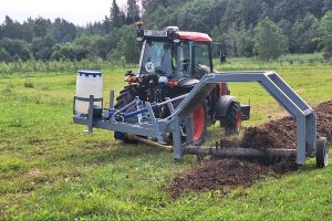 Traktors ar komposta maisītāju veido komposta kaudzi lauksaimniecības laukā.
