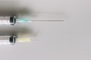 Divas medicīniskās šļirces ar adatām uz gaiša fona